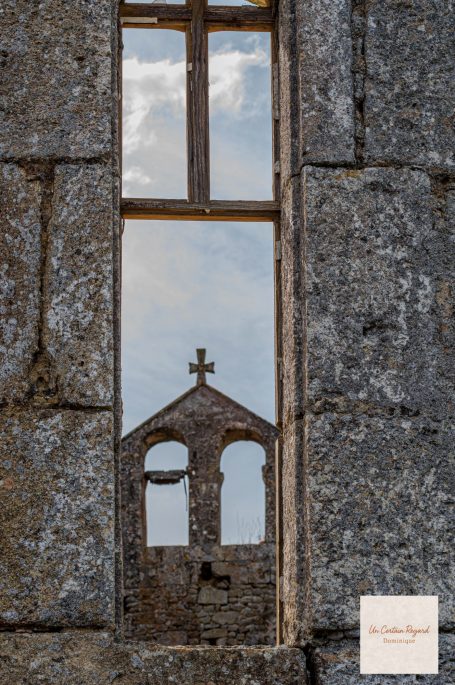 Une croix apparaît dans une fenêtre, encadrée par des murs en pierre.